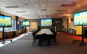 Conference room surrounded by 4 very large televisions with yellows daisies on the screen